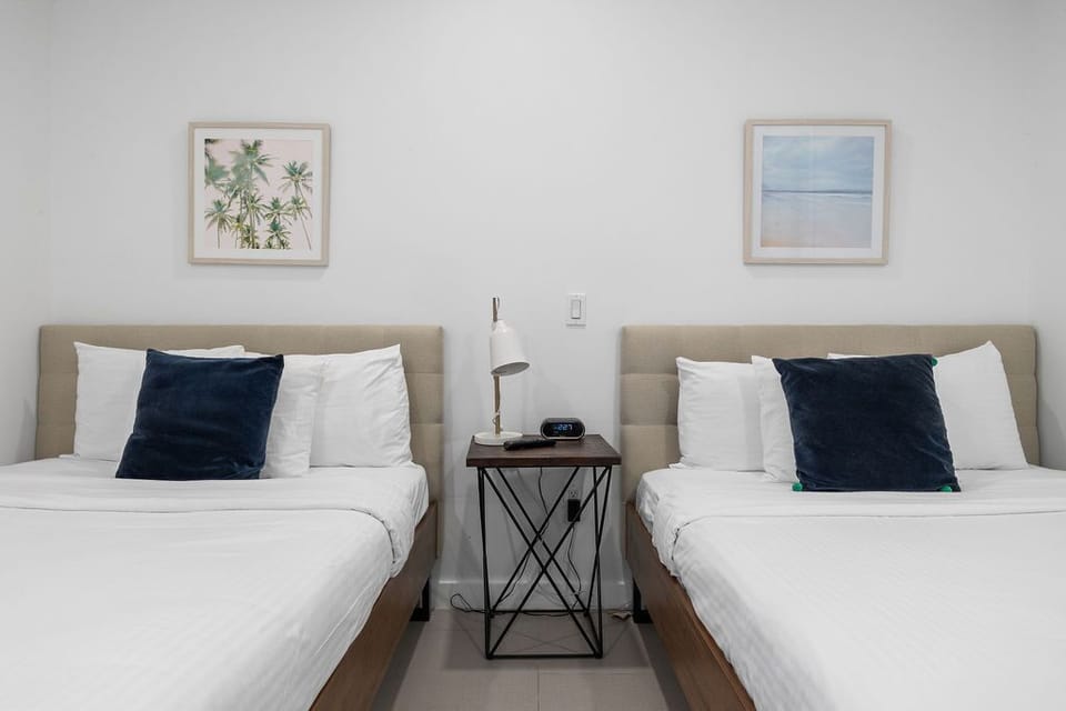 Drift off in crisp white linens and matching twin beds with elegant navy accent pillows. Coastal artwork and a reading lamp create your tranquil escape.