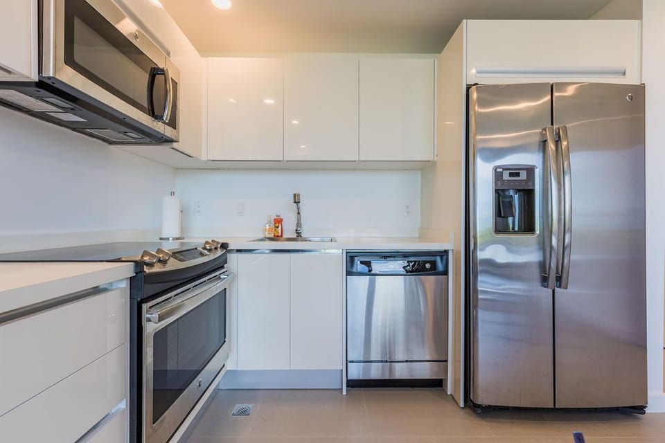 This fully equipped kitchen features sleek stainless-steel appliances, modern white cabinetry, and ample counter space perfect for preparing your favorite meals during your stay.
