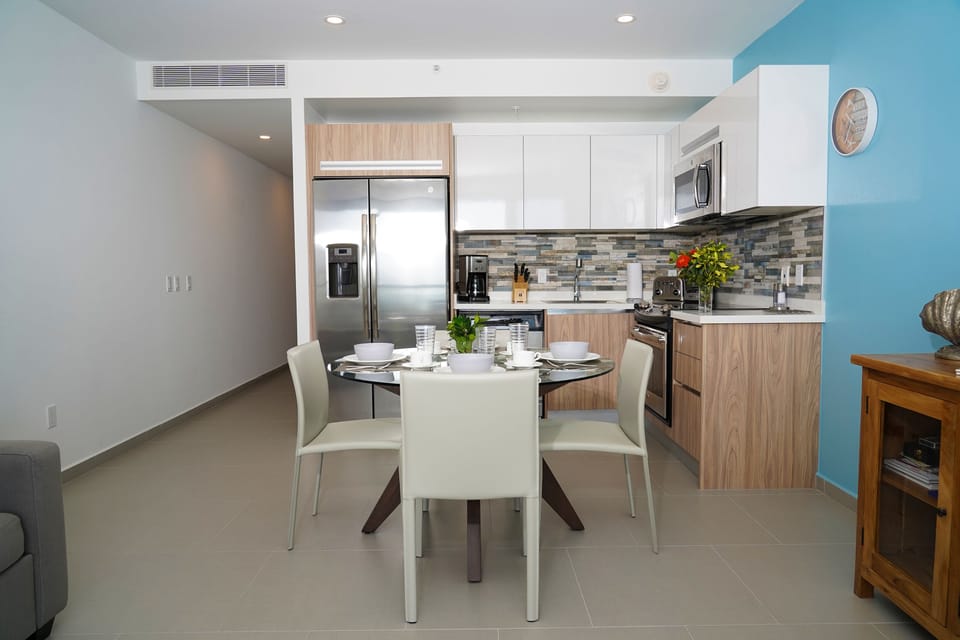 Your modern kitchen and dining area features sleek appliances, stylish cabinetry, and a cozy table ready for your meals, all within a bright, open space designed for comfort.
