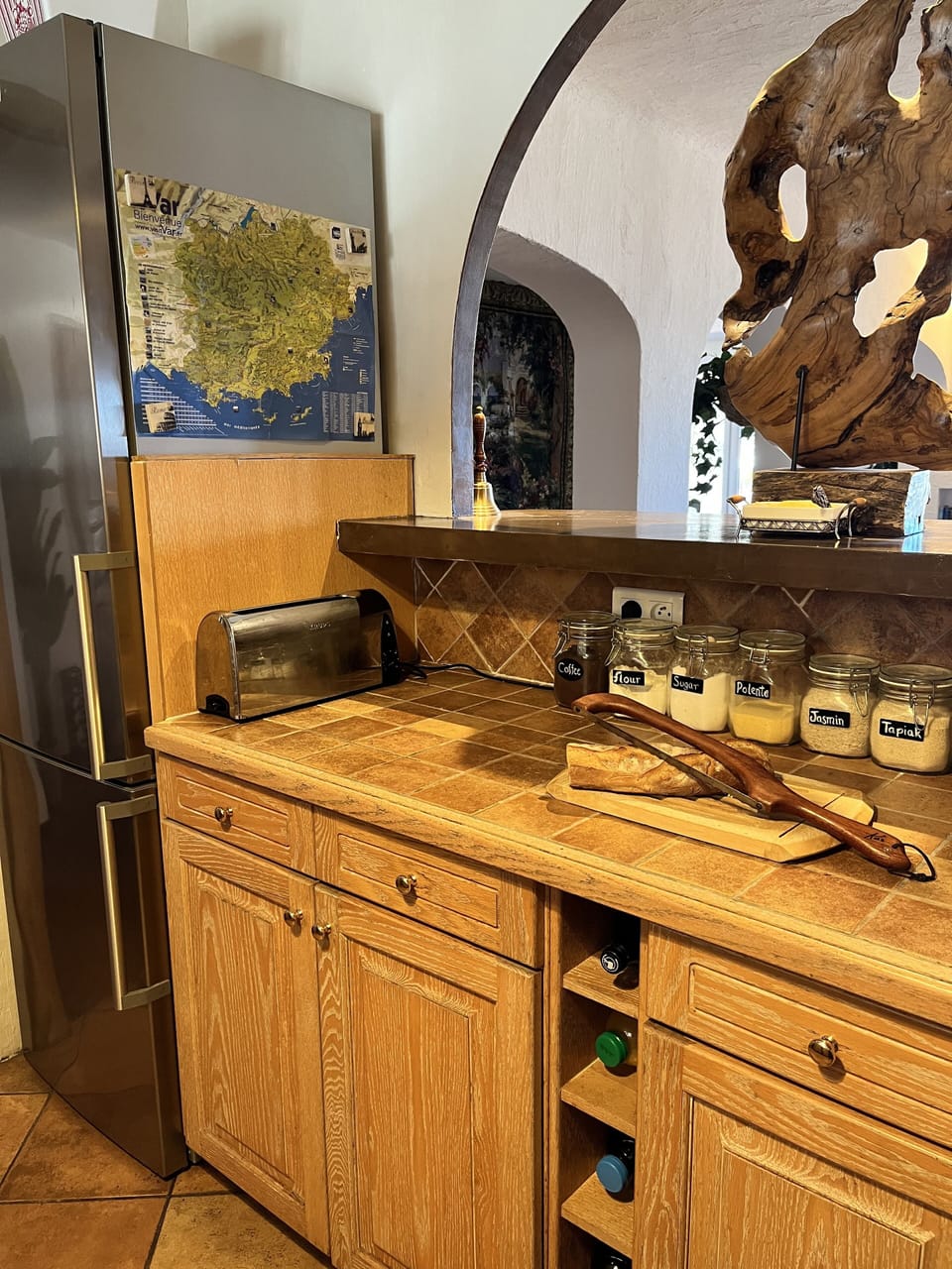 Open kitchen from hall with American frig/freezer, plates and kitchen ware here