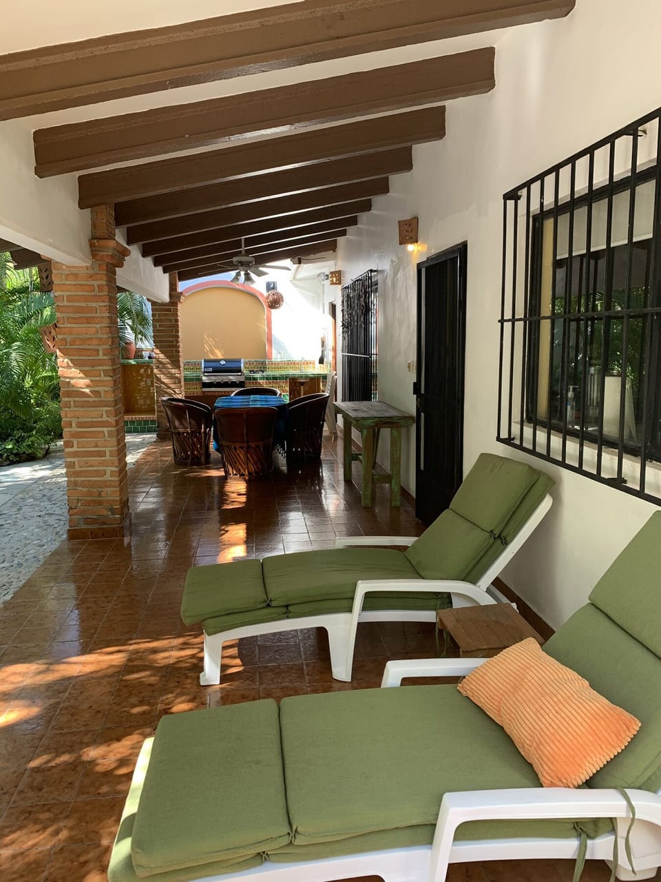 Daytime living space is outside on a large patio with roofed area for shade.