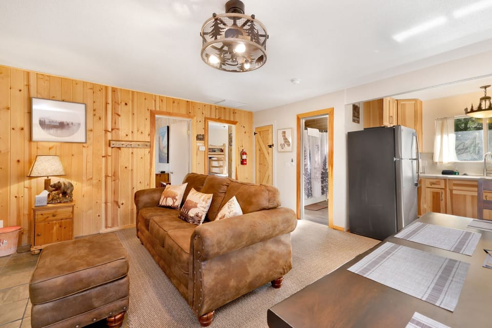 Cozy mountain living room with a stone fireplace, comfy seating, and smart TV—perfect for relaxing evenings, movie nights, and warm cabin vibes after outdoor adventures.