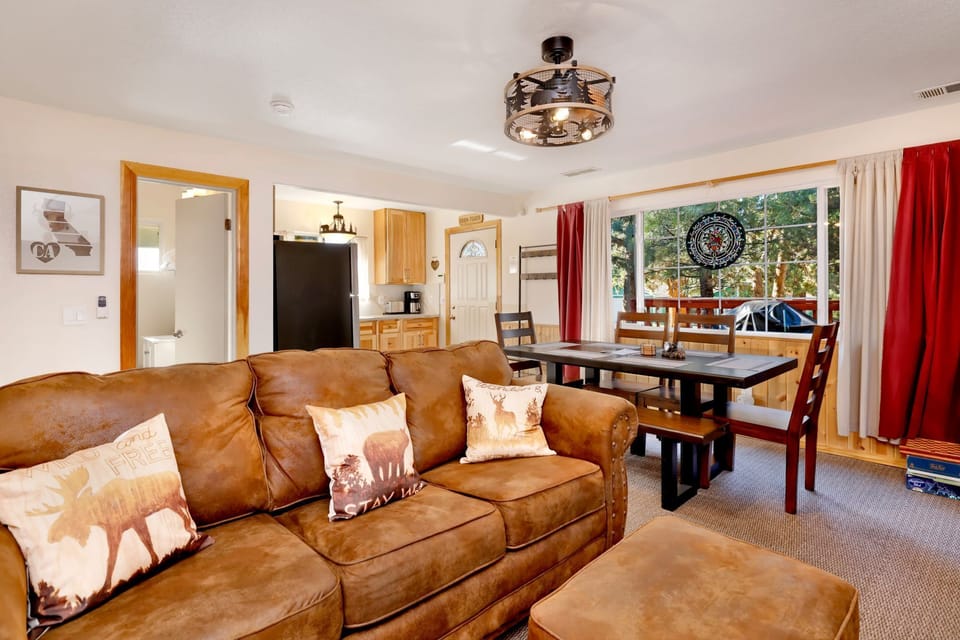 Cozy mountain living room with a stone fireplace, comfy seating, and smart TV—perfect for relaxing evenings, movie nights, and warm cabin vibes after outdoor adventures.