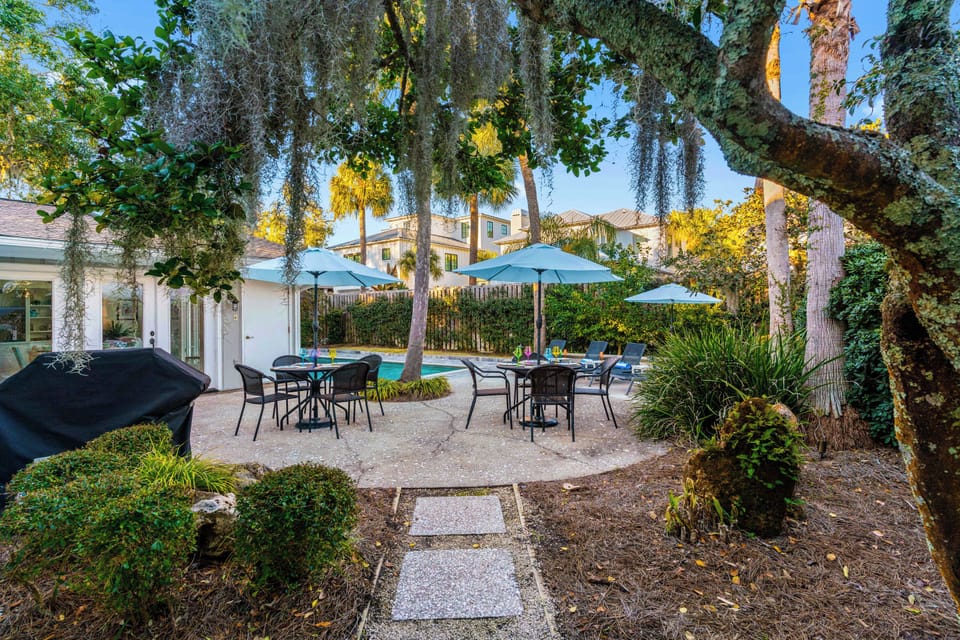 Your private backyard oasis awaits with a sparkling pool, shaded dining spots, and lush tropical landscaping for ultimate relaxation.