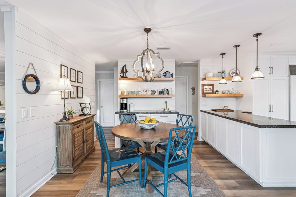 You'll love preparing meals in this bright coastal kitchen with its charming shiplap walls, granite counters, and cheerful blue dining chairs.