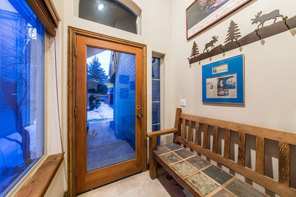 Step into a warm and welcoming entrance with rustic wooden bench seating, coat hooks, and scenic views through large windows. The perfect space to kick off your boots and feel right at home from the moment you walk in.