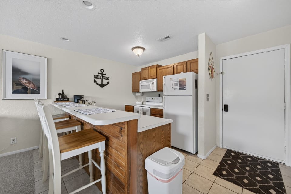 Your fully-equipped kitchen features warm wood cabinetry, modern appliances, and a breakfast bar—perfect for whipping up meals or enjoying morning coffee together.