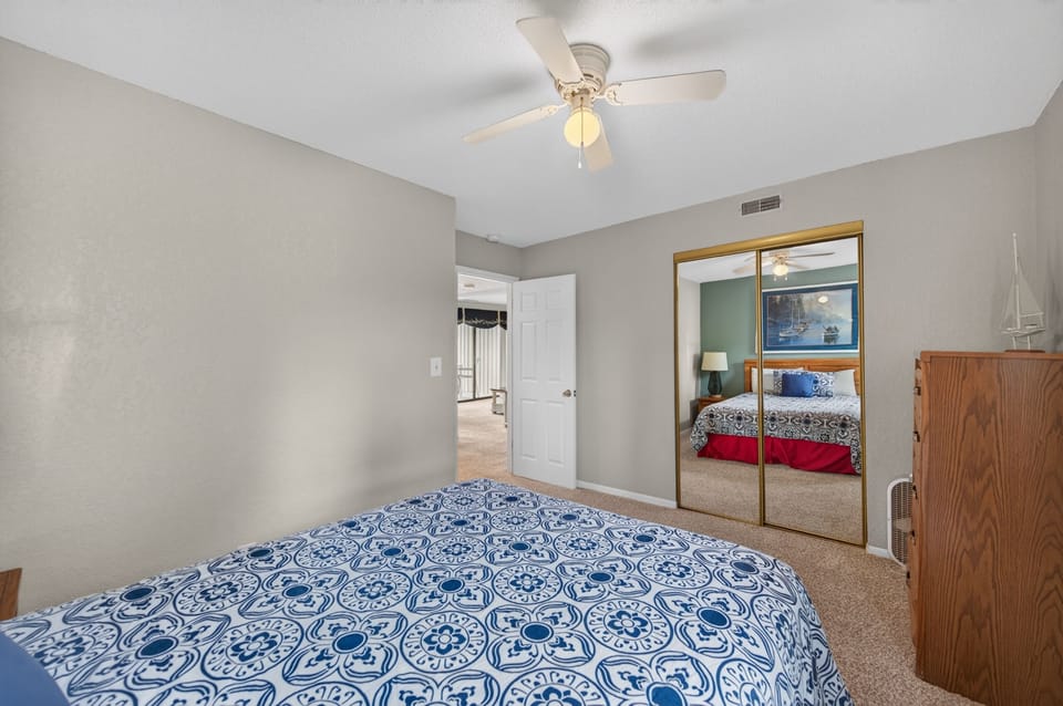 Your serene bedroom features a comfy bed, ceiling fan for cool nights, mirrored closet for storage, and soft carpet underfoot. Unwind in this peaceful retreat.