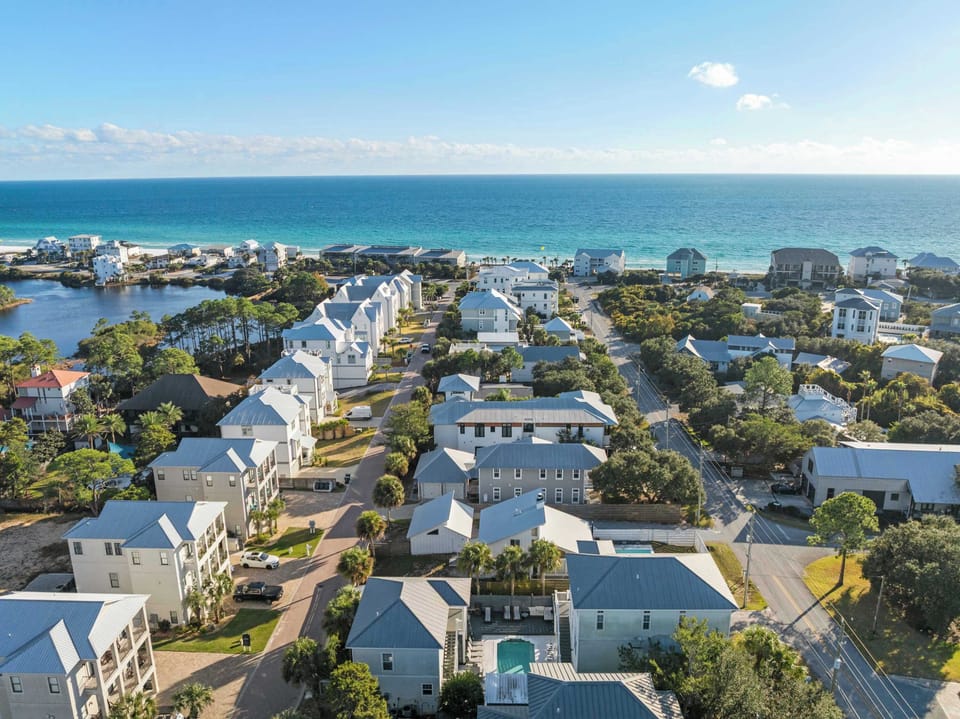 Elevated aerial showing rows of homes leading toward the water under clear blue skies.