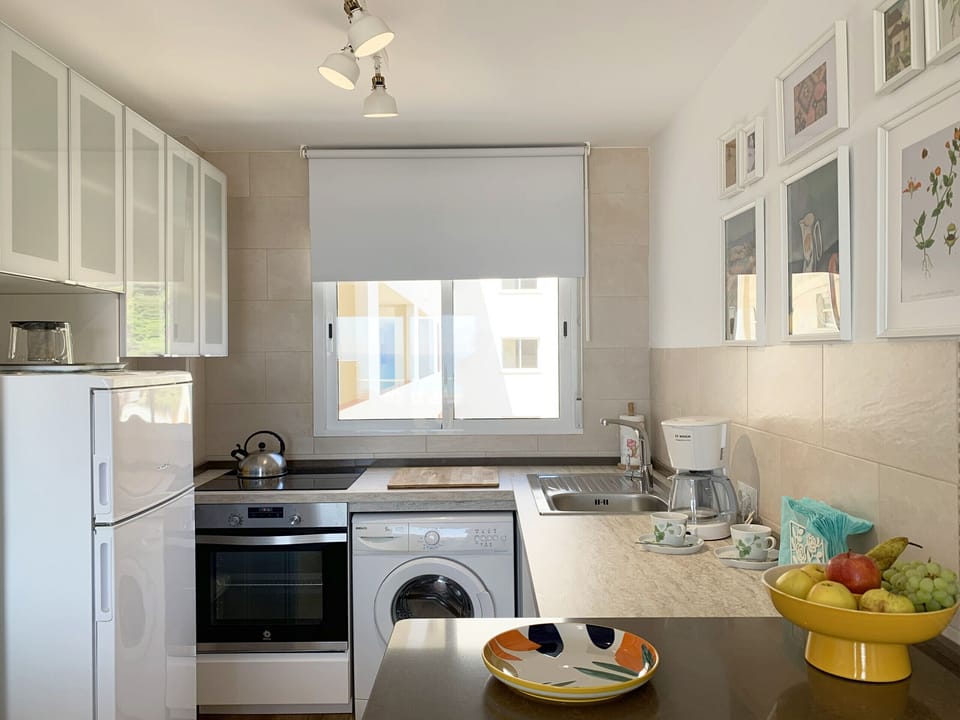 Kitchen with pleasant natural lighting, stove, refrigerator and all the necessities