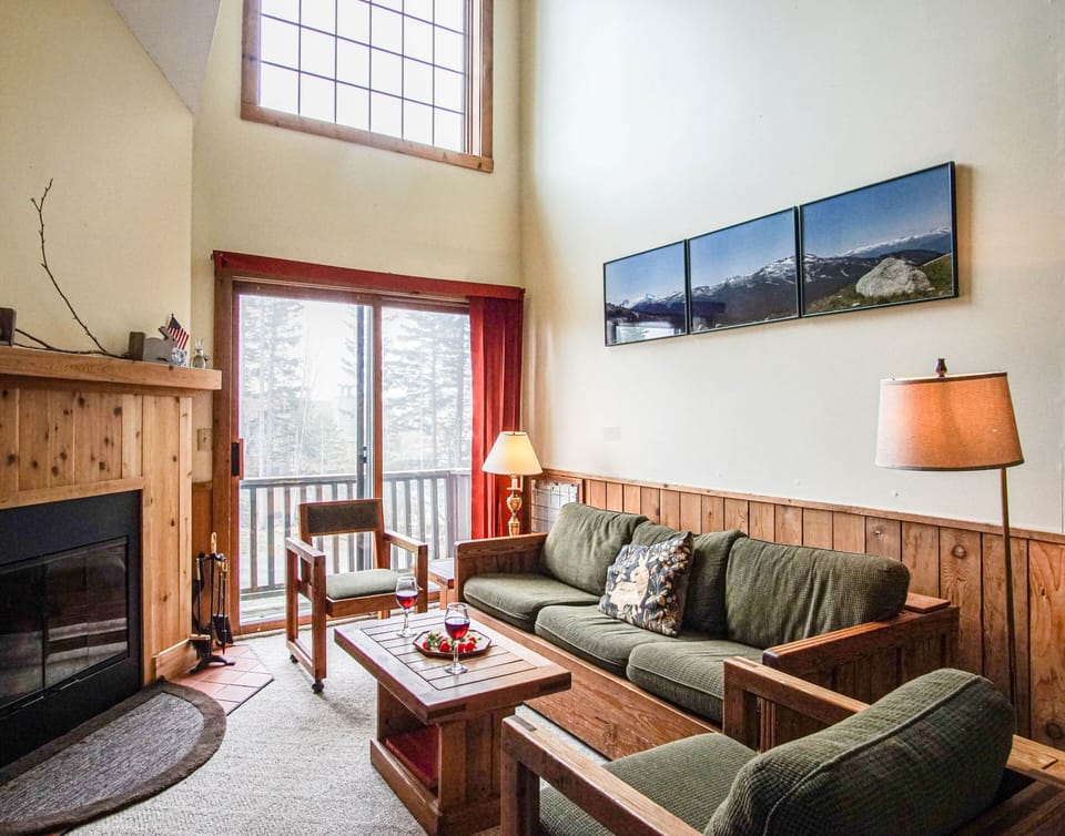 View of living area with queen sleeper sofa, wood fireplace.