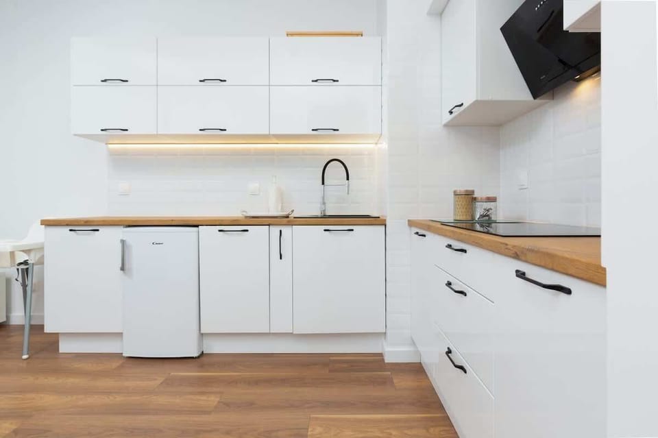 A spacious open kitchen and living area with white cabinetry, wooden countertops, and natural light.
