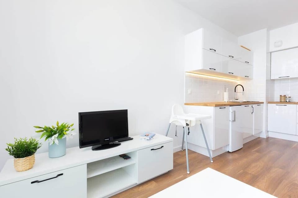 A bright living room with a TV, minimalist shelving, and a stylish white interior.