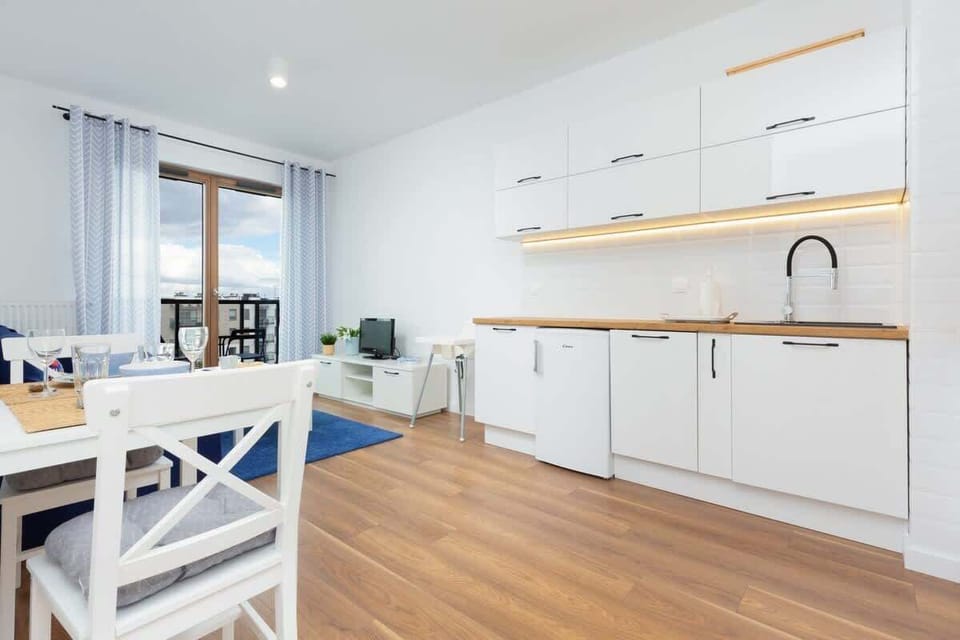 A modern kitchen featuring sleek white cabinets, wooden countertops, and an induction stove.