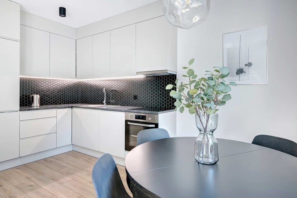 A large, well-lit living and dining area with modern furnishings and an elegant pendant lamp above the table.