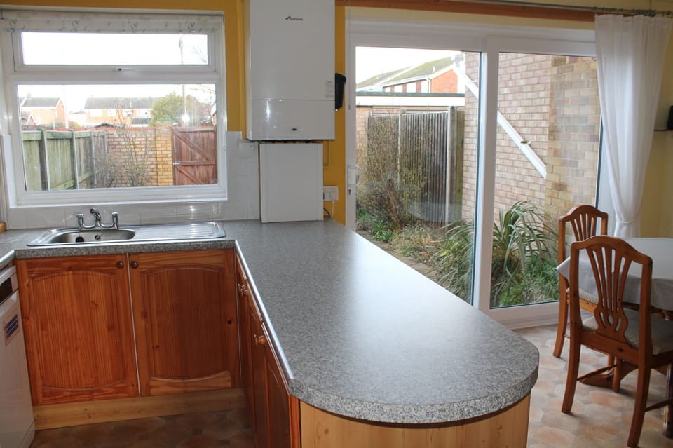Sliding door leading into fully enclosed back garden with parking behind