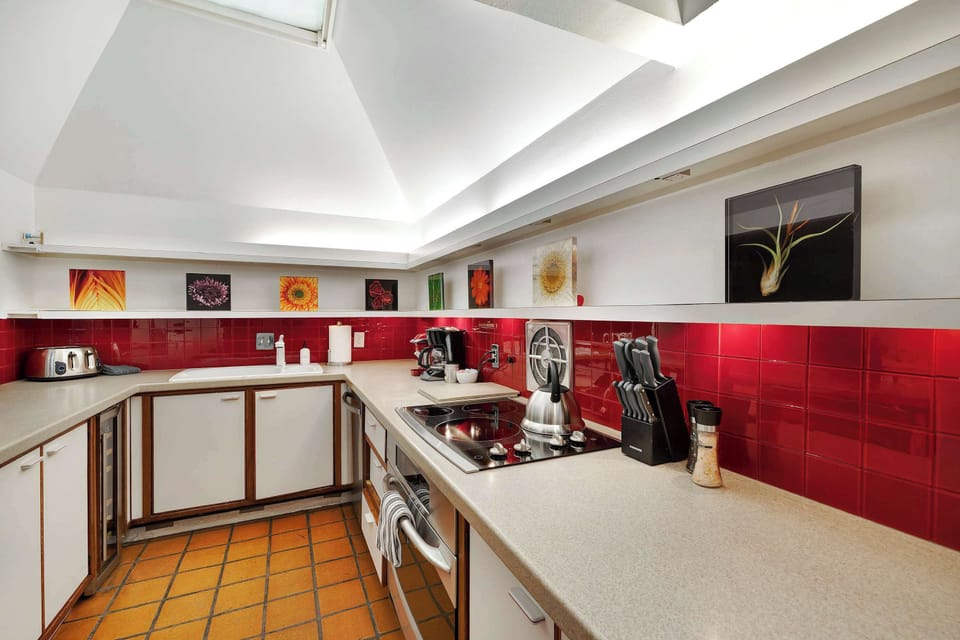 Fully equipped kitchen with a bold red backsplash and everything you need to cook, brew, and gather in style.