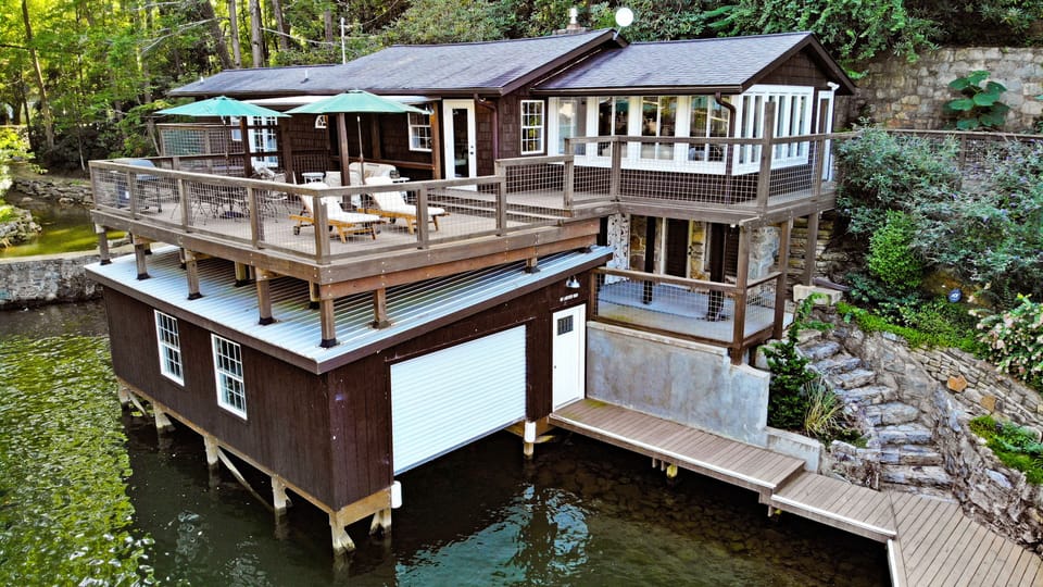Large boathouse deck has lounge chairs, sun umbrellas, covered seating area, gas BBQ grill and dining table for 6