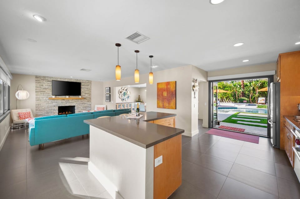 Sleek open-concept kitchen flows seamlessly to your vibrant living space, with a sparkling pool view beckoning beyond glass doors.