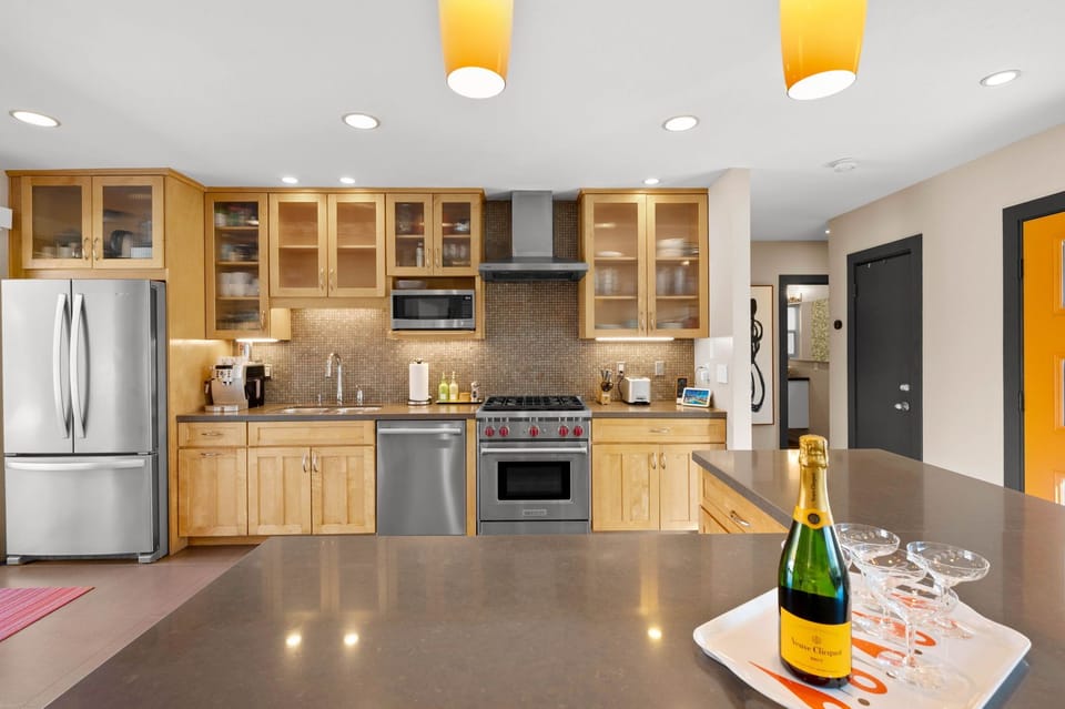 Your fully equipped gourmet kitchen awaits with sleek appliances, ample storage, and champagne ready for your celebration.