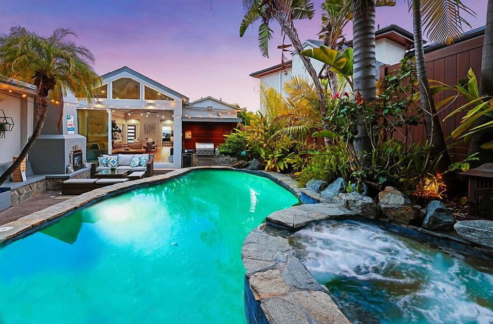 Escape to your private oasis featuring a heated pool with a soothing waterfall, hot tub, and an outdoor lounge with BBQ and fireplace — the perfect place to unwind and recharge.