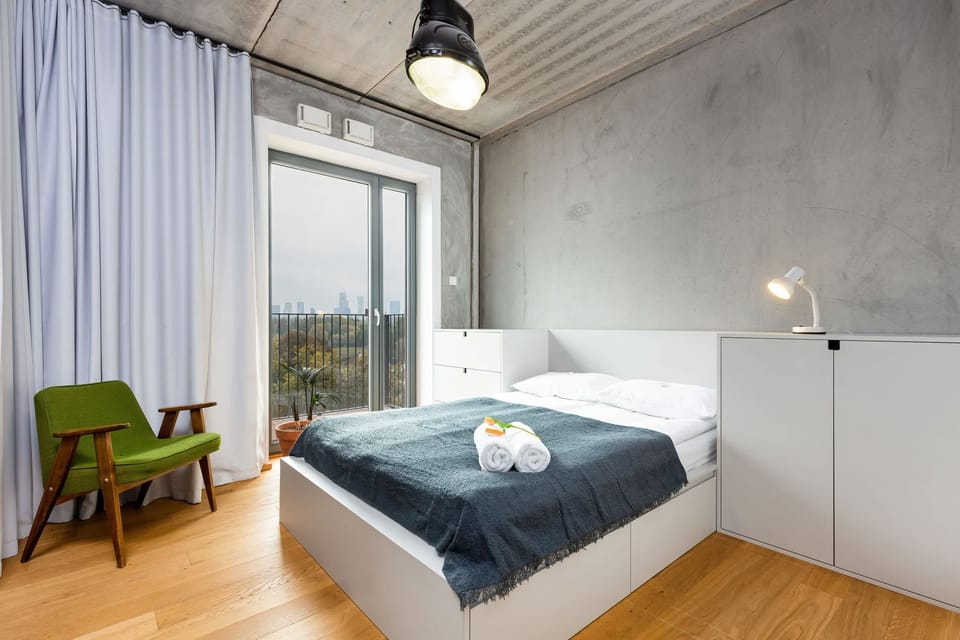 A stylish bedroom featuring a comfortable double bed, wooden floors, and a large window offering plenty of natural light.