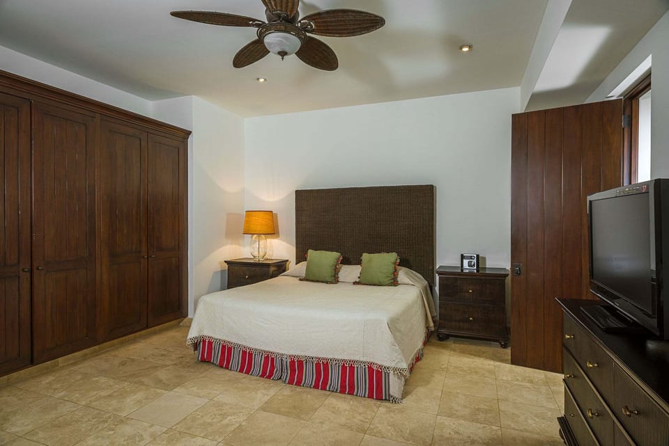A guest bedroom at Casa Cielo at Pedregal with a king bed, a television and fitted wardrobes.