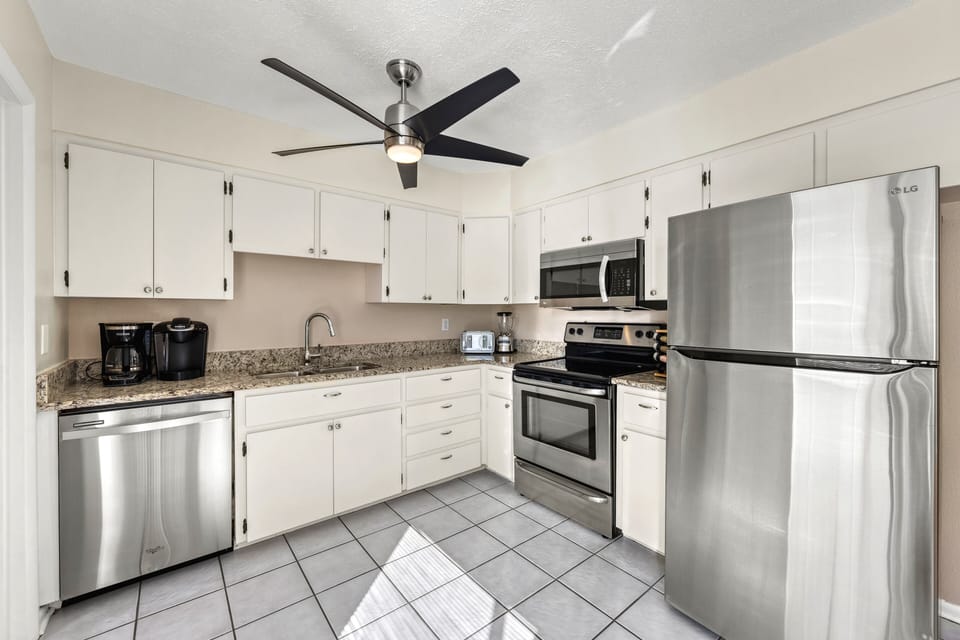 The open kitchen offers plenty of bright space for cooking and gathering, with a clean coastal style that feels fresh and inviting.