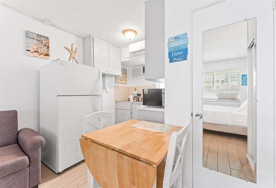 Bright studio space with a queen bed, TV, window AC, and a twin sleep sofa for additional sleeping — a cheerful coastal retreat close to the sand.