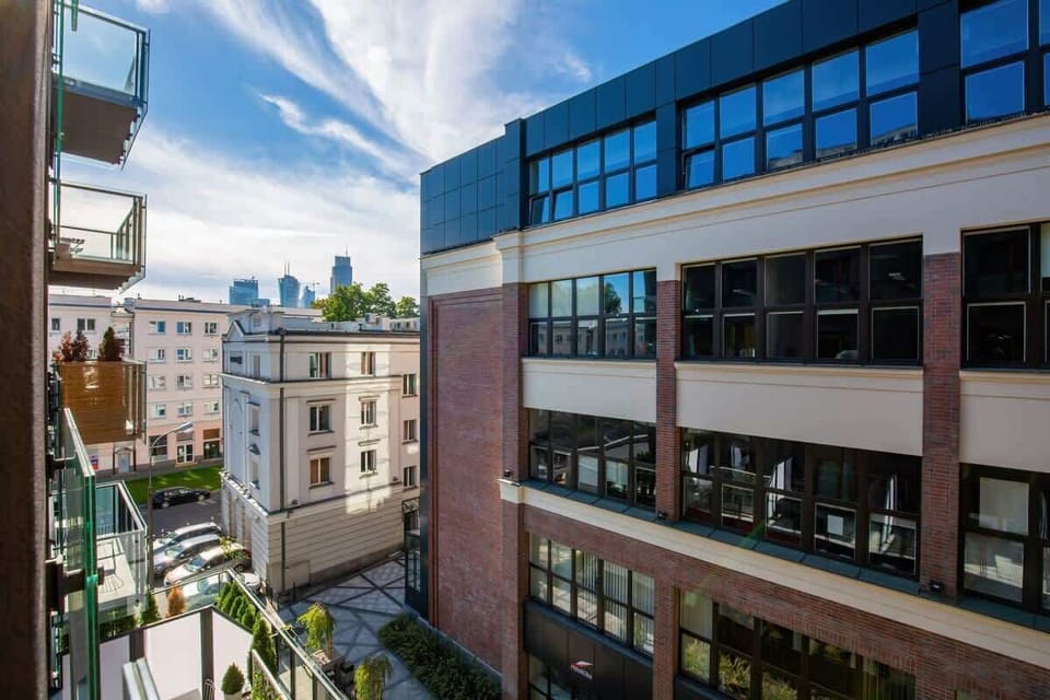 The window offers a view of a modern residential building with glass facades and greenery.