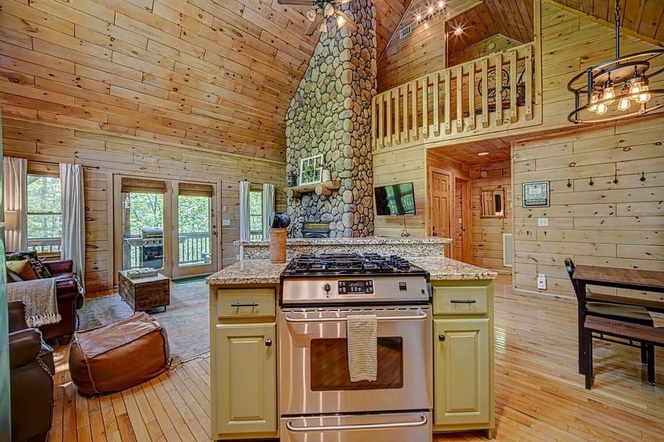 Stainless steel appliances, granite countertops, stone fireplace, and vaulted ceiling