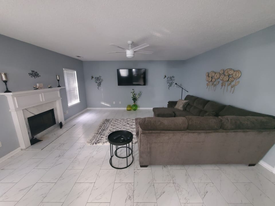 spacious Family Room with wall mounted Smart TV, ceiling fan, snuggly couch