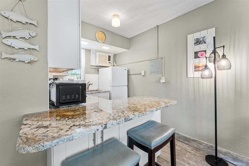 Clean tiled walk-in shower bathroom with vanity sink, mosaic floor, fresh towels, and toiletries included.