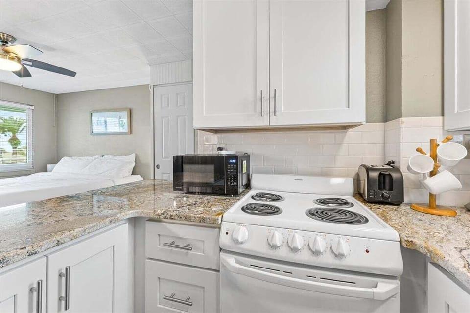 Clean tiled walk-in shower bathroom with vanity sink, mosaic floor, fresh towels, and toiletries included.