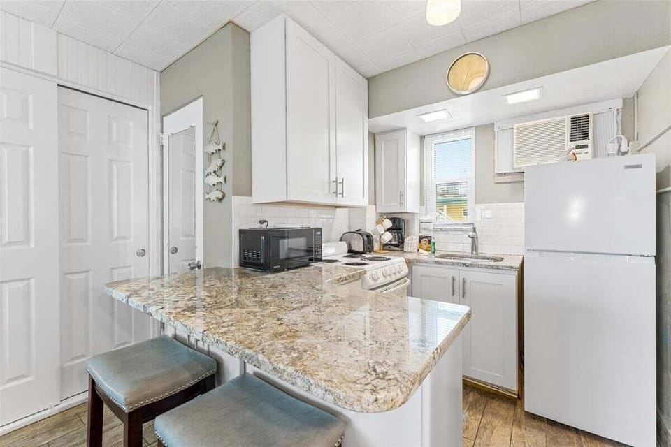 Clean tiled walk-in shower bathroom with vanity sink, mosaic floor, fresh towels, and toiletries included.