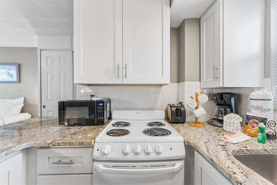 Clean tiled walk-in shower bathroom with vanity sink, mosaic floor, fresh towels, and toiletries included.