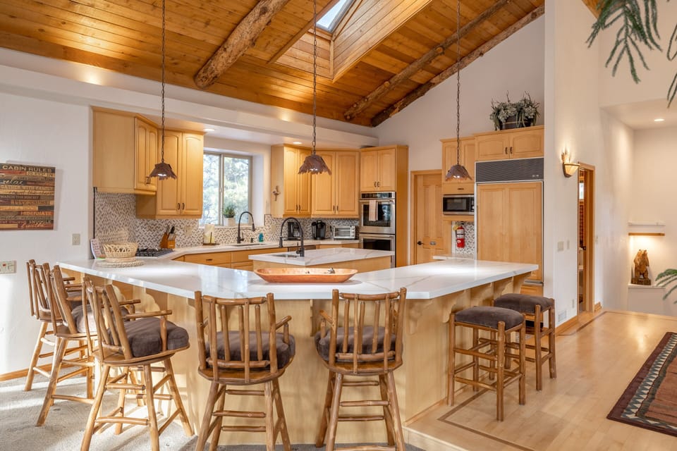Kitchen, Island with sink, Reg coffee maker, Fire extinguisher, dishwasher, and wrap-around kitchen counter with stools for extra seating.