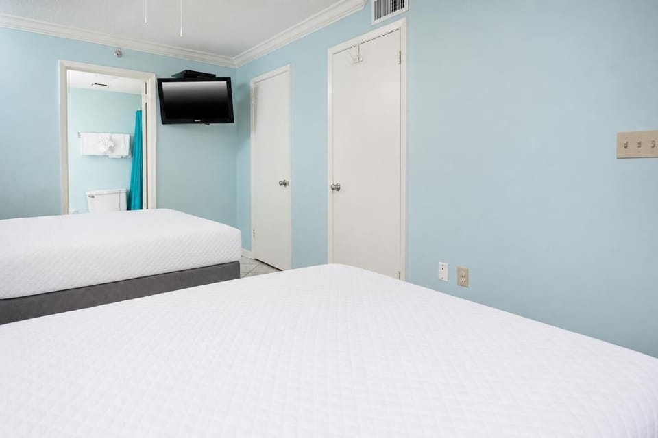 Relax in the inviting guest room with two double beds, a TV, and a calming blue color scheme