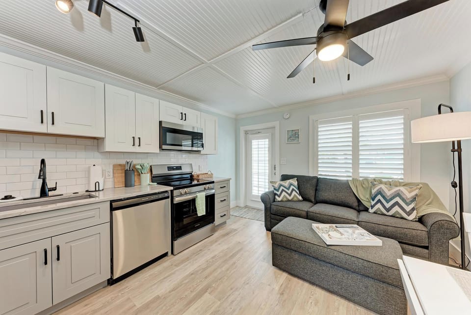 Fully equipped kitchen with stainless steel appliances, white cabinetry, and adjacent living and dining area