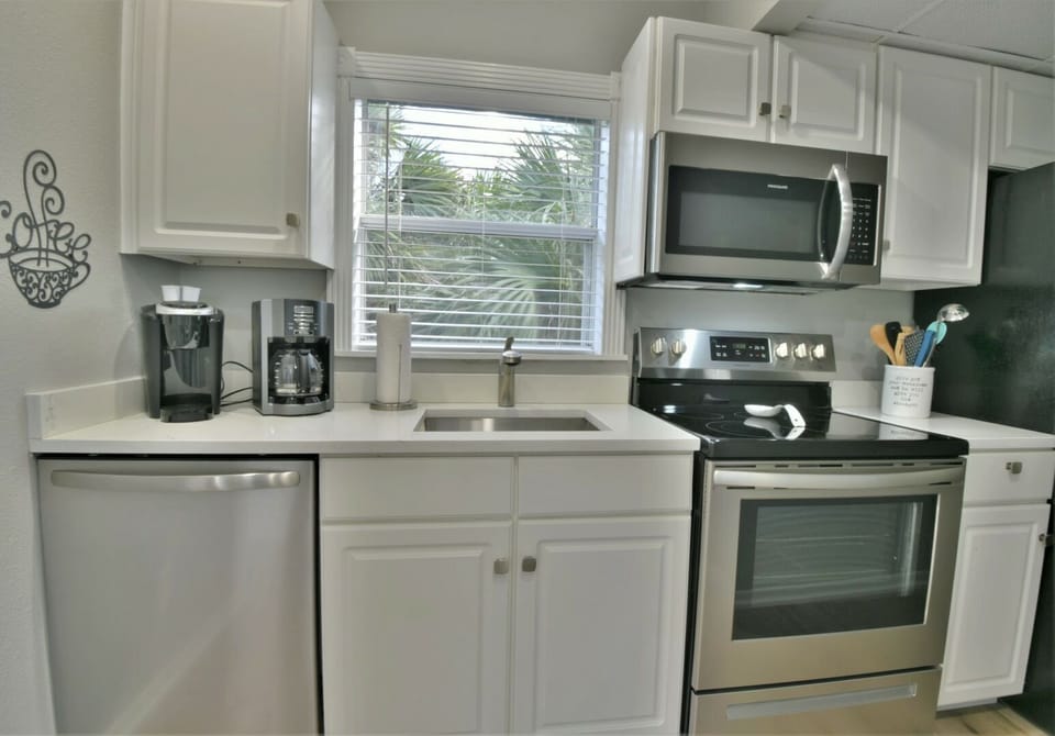 Kitchen with white cabinets, stainless steel microwave, electric range, and dishwasher