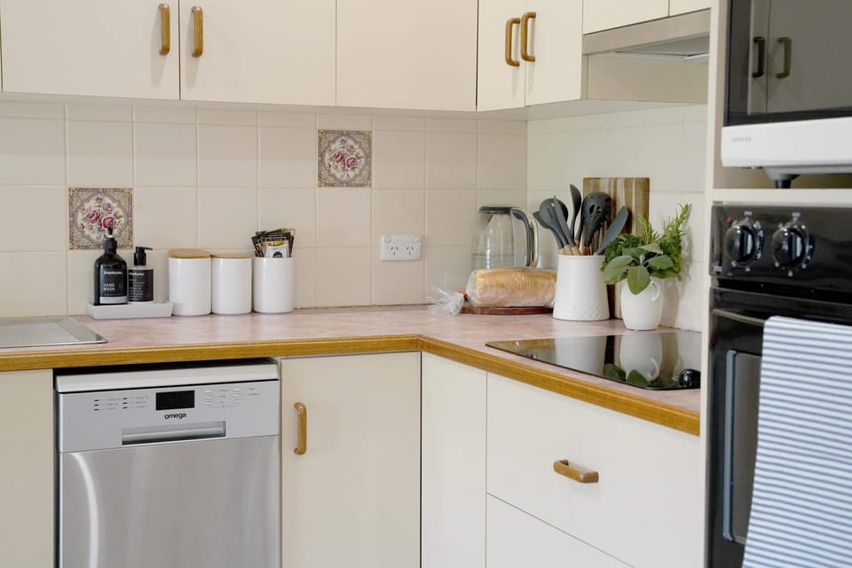 Kitchen featuring dishwasher, oven, stove, fridge & basic utensils & cookware.
