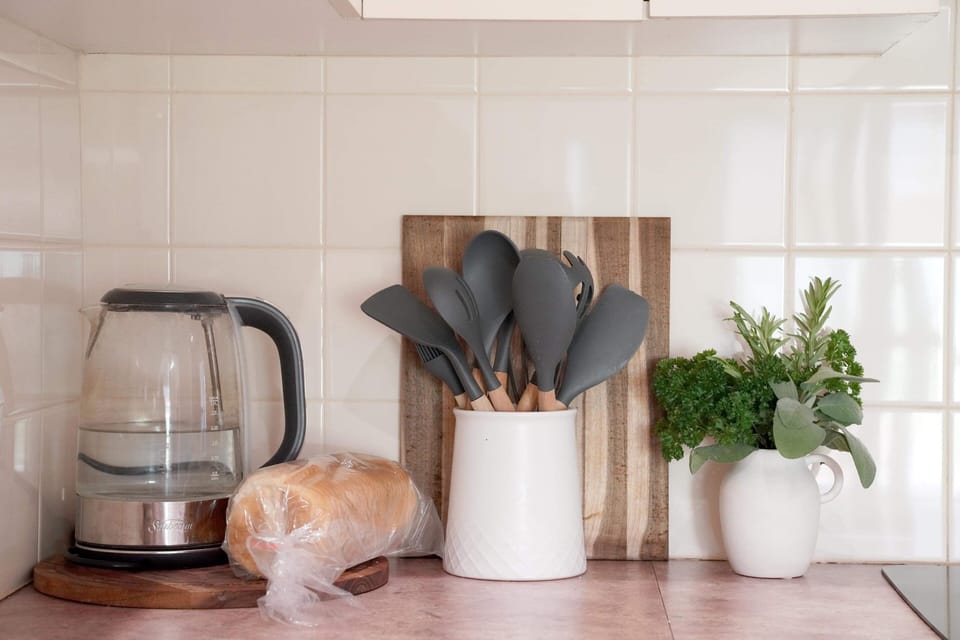 Kitchen featuring dishwasher, oven, stove, fridge & basic utensils & cookware.