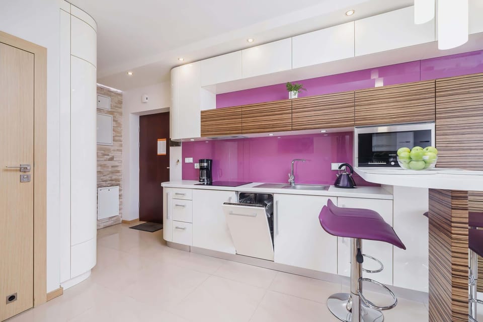 A vibrant kitchen with purple cabinetry and a breakfast bar equipped with sleek bar stools. The design combines style and functionality.
