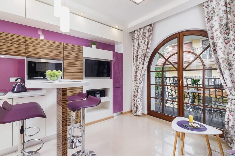 A dining space with a small table and chairs set near a window. The combination of white and purple creates a modern, clean aesthetic.