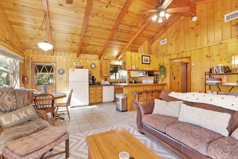 Spacious open-concept cabin with comfortable seating, rustic wood interiors, and an easy flow into the kitchen and dining area perfect for groups.