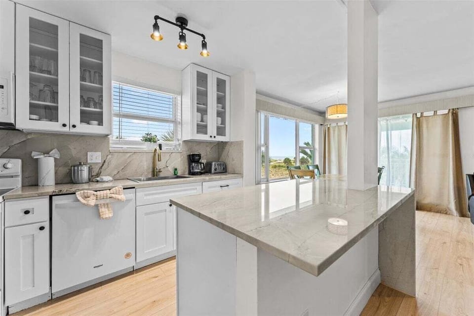 Fully equipped kitchen with granite counters, white appliances, dishwasher, electric range, microwave, and a large island — plenty of space for cooking and gathering.