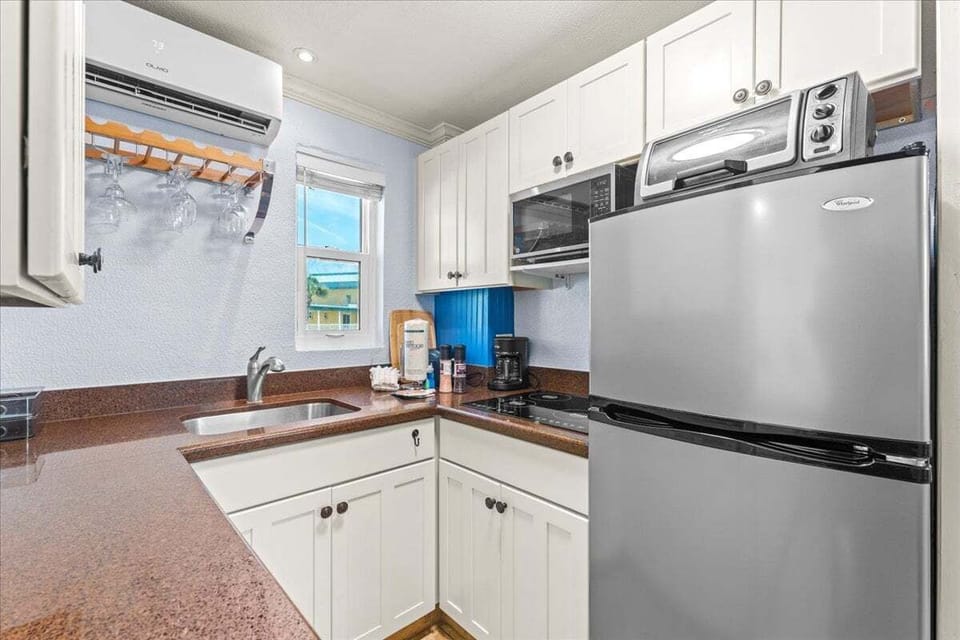 Compact kitchen with a stainless fridge, induction cooktop, microwave, and coffee maker — everything you need for easy meals during your stay.