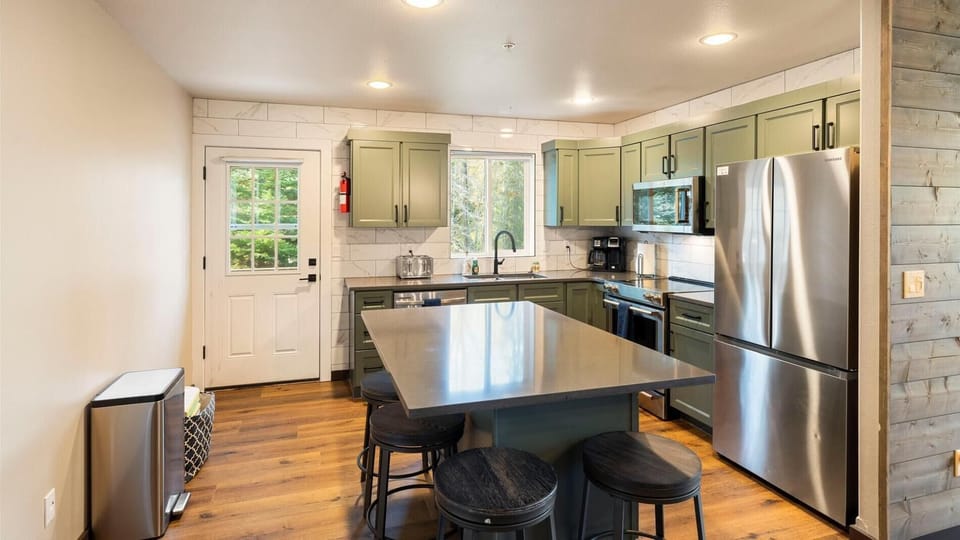 Newly remodeled open concept fully stocked kitchen with breakfast bar seating for 4 and access to deck with hot tub, outdoor dining space, and BBQ grill.