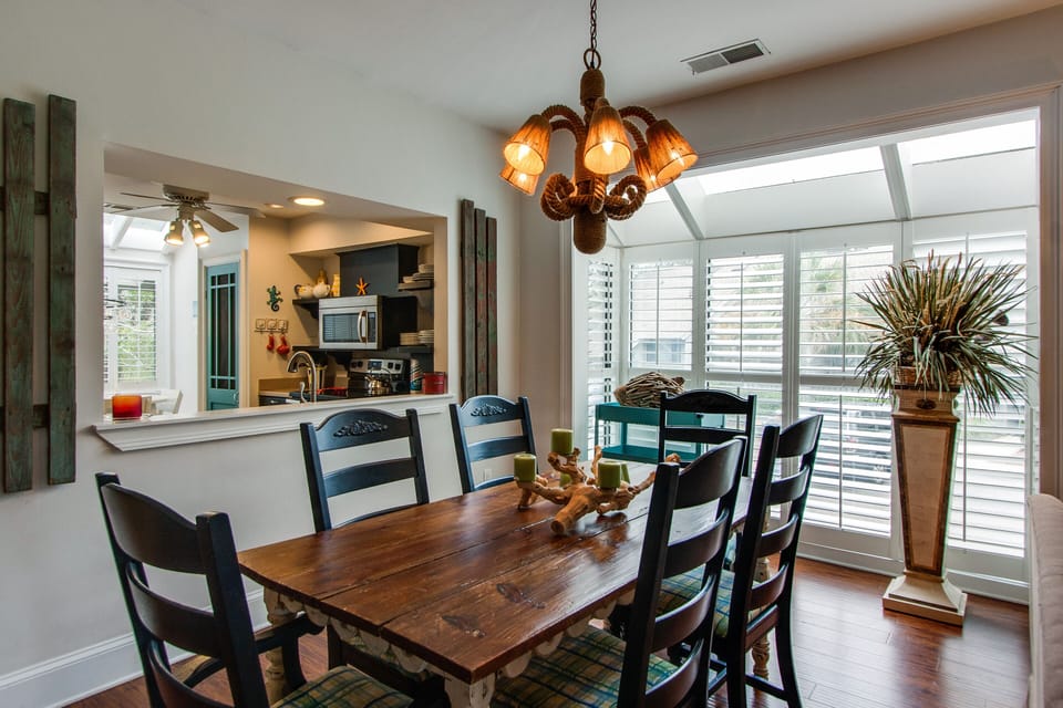 This bright dining area is ideal for shared meals and easy entertaining, featuring a table with seating for six and a stylish chandelier overhead.