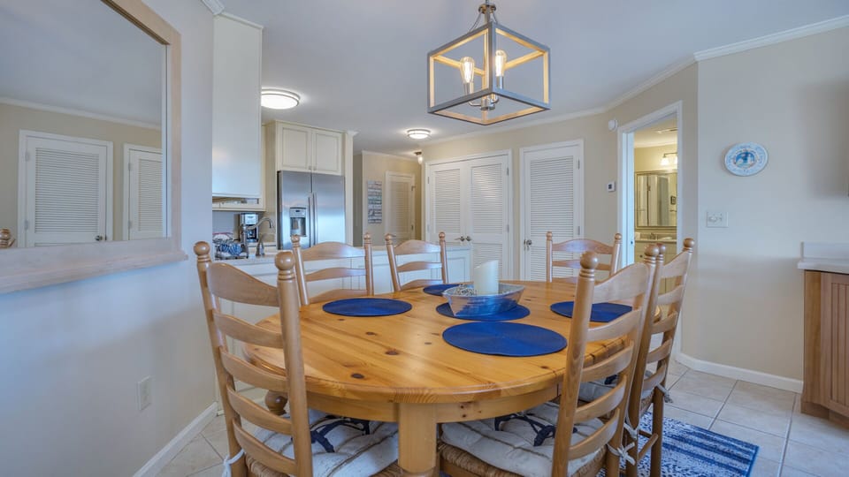 This light-filled dining area offers a comfortable gathering space with seating for six, set beneath a classic lighting that adds a warm coastal touch.